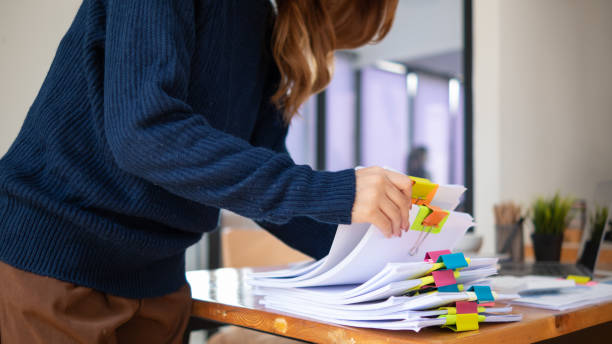 istock secretary searches through stacked documents on desk in office to find lease within stacked documents just before meeting. concept difficulty in finding hire purchase contract from stacked documents 1498465948