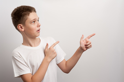 A teenager points with his fingers at an imaginary thing during a fashion photoshoot