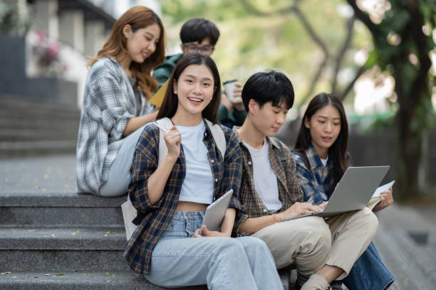 istock Potrait of young Asian college students working on group project while sitting on staircase of college campus. 1498467463