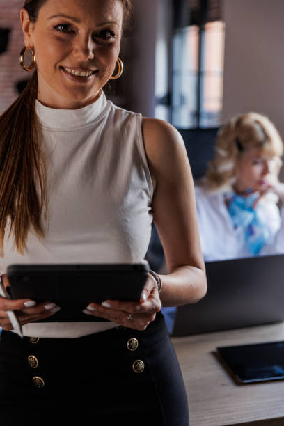 istock Businesswoman sitting at the edge of a desk, using digital tablet while working on a project 1498467593