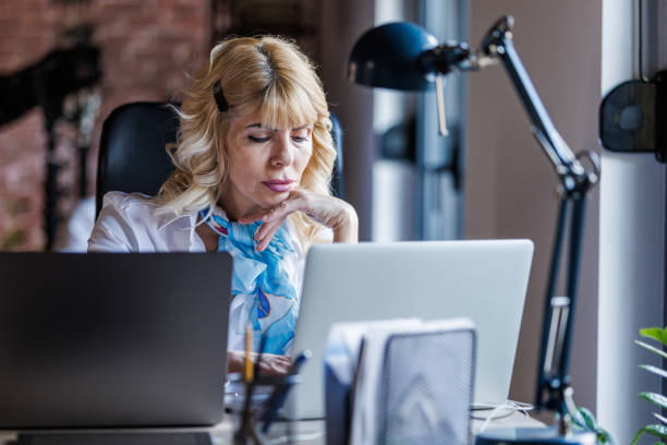istock Charming blond businesswoman sitting at her desk, using laptops and working on a project 1498467861