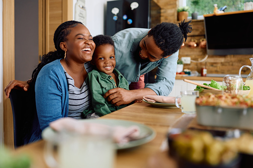 Happy African American family having fun while having a meal in dining room. Focus is on boy.