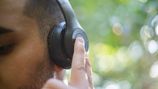 Young man listening to music with wireless headphones in nature