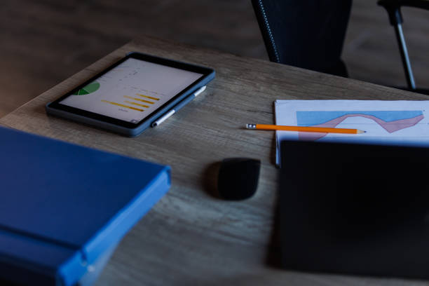 Close up shot of a digital tablet, documents, pencil and a file folder on a desk during office hours. Part of a series.