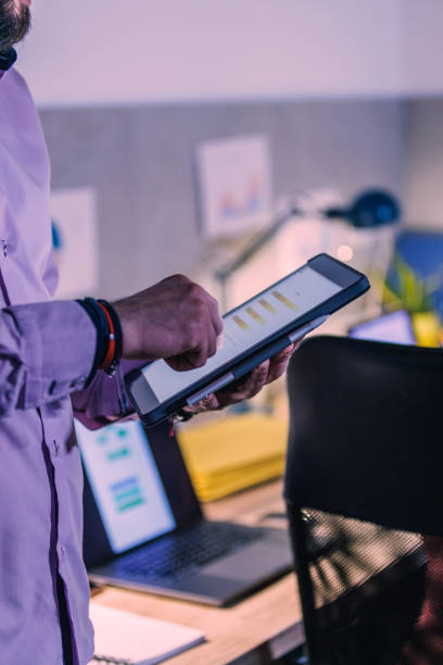 istock Unrecognizable businessman using digital tablet while working late at the office 1498469290