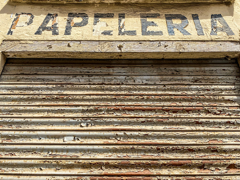 Low angle view of old weathered stationary shop sign in Spanish language