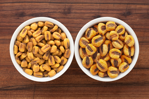 Top view of two bowls side by side with varieties of salted fried corn kernels