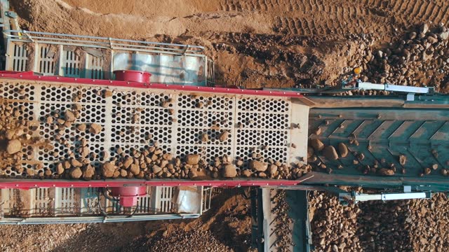 Heavy machinery loading stones conveyor belt crushing screening plant. Aerial top view