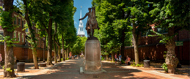 Boston, Massachusetts, USA - July 19, 2022:  Paul Revere statue on the historic Boston Freedom Trail with the Old North Church steeple in behind in Boston Massachusetts USA