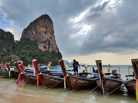 Long tail boats moored in Railay beach at sunset, one of the most famous beaches in Krabi and one of the most beautiful places in Thailand.
