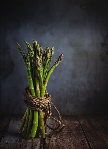 bunch of green fresh asparagus on rustic wooden background.