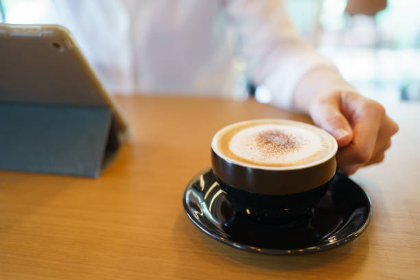 Beautiful latte art on hot latte coffee served in a ceramic white cup on wooden table close up. Basic Tuilip latte art decorated over the latte coffee.