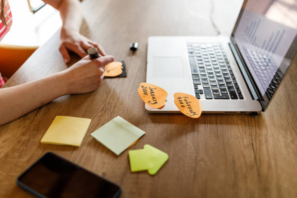 istock Young woman writing something on a sticky note at her desk 1498484709