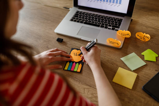 istock Young woman writing something on a sticky note at her desk 1498484837