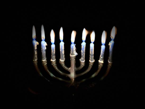 High angle view, part of lighted Menorah on eighth night of Hanukkah isolated against black background. Wax