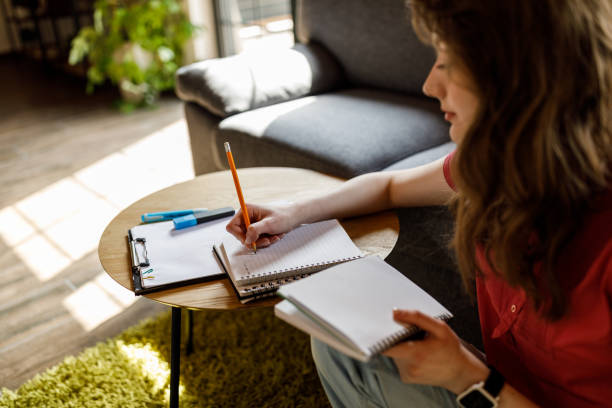 istock Female student doing research and studying at coffee table in living room 1498488476