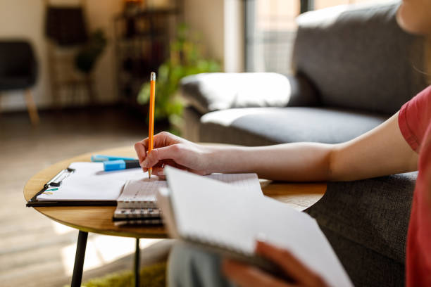 istock Female student doing research and studying at coffee table in living room 1498488543