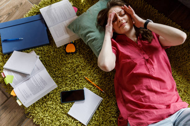 istock Tired student lying ont the floor, rubbing her eyes while tired from studying 1498488776