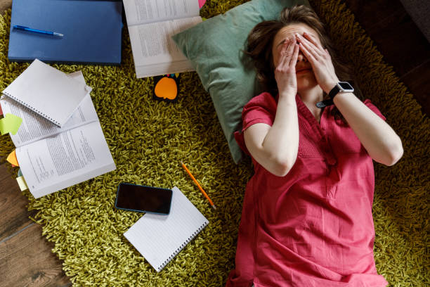 istock Tired student lying ont the floor, rubbing her eyes while tired from studying 1498488789