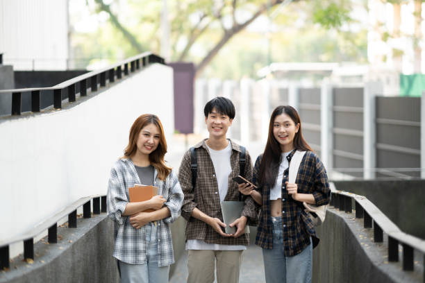Group of happy students walking with notebook and laptop computer, walking into the classroom.
