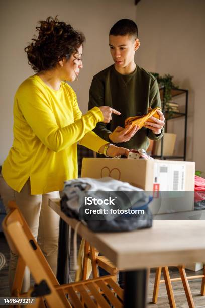 Teenage Boy And His Mother Sorting Out Clothes That Hes Outgrown Stock Photo - Download Image Now