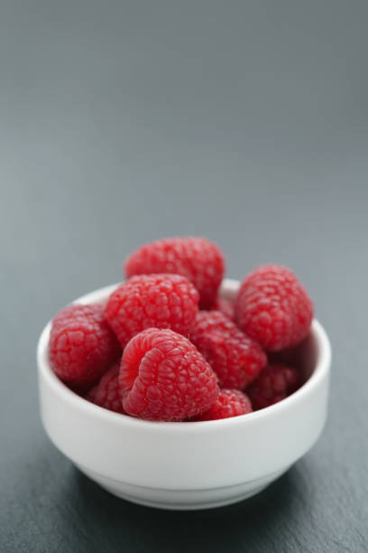 istock fresh raspberries in white bowl on slate board 1498494394
