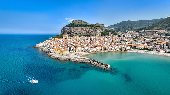 Cefalù City Aerial Drone Point of View Panorama over the turquoise Mediterranean sea of north Sicily's tyrrhenian coast. Famous Cefalù Cathedral in the village center and iconic hill La Rocca in the back of Cefalu Town. Cefalu, Tyrrhenian Coast, Gibilmanna, Northern Sicily, Sicily Island, Italy, Southern Europe.