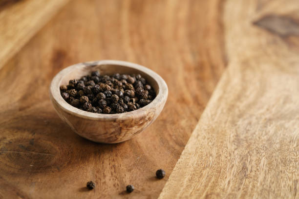istock black dry pepper in wooden bowl on table 1498495075