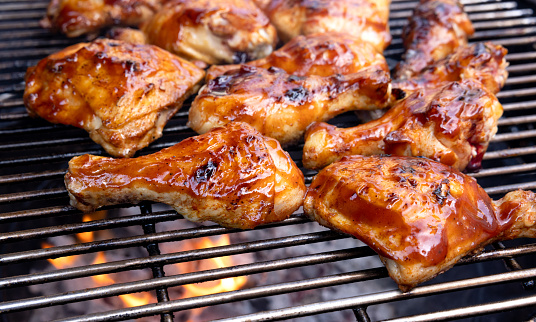 High quality stock photo of barbecued chicken for a summer time party at home in the backyard roasting over open charcoal coals.