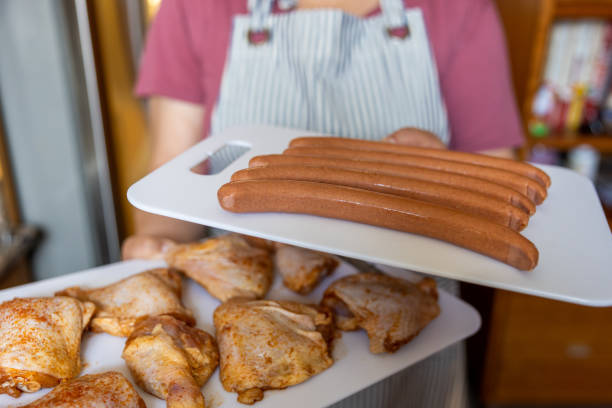 High quality stock photo of an Asian-American woman preparing and barbecuing chicken for a summer time party at home in the backyard.