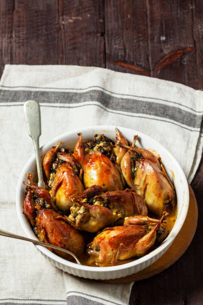 istock Baked quail stuffed with mushrooms, eggs and bread in a ceramic form on a wooden table. 1498499664