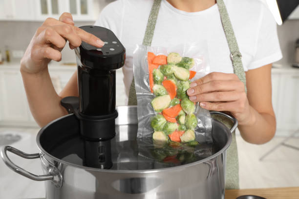 istock Woman putting vacuum packed vegetables into pot and using thermal immersion circulator, closeup. Sous vide cooking 1498500850