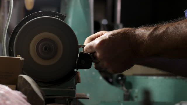 Man worker sharpens a drill at the grinder