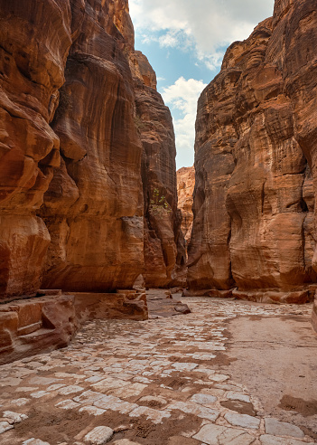 Al Siq Canyon in Petra, Jordan, pink red sandstone walls on both sides, tiled stones footpath