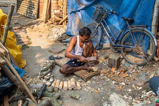 Rural West bengal india on march 12th 2023: Village man making wooden dolls at their home.