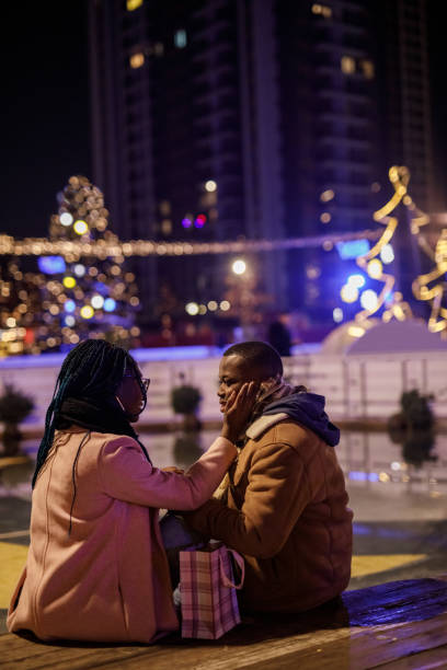 couple heureux se souriant lors d’un rendez-vous romantique au parc de noël - pat on back photos et images de collection