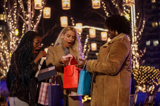 istock Three joyful girlfriends exchanging Christmas presents at the Christmas park 1498507115
