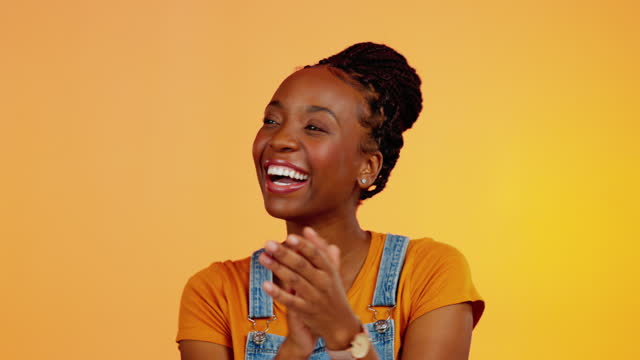 Face, applause or happy black woman celebrate achievement, success goals or winning congratulations. Happiness, winner or studio person celebration for news, victory and clapping on orange background