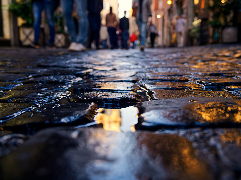 Wet cobblestone footpath in old town. Lights reflecting in cobble road after rain, Rome, Italy