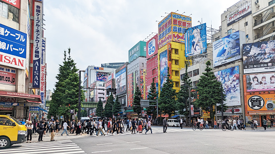 May 22, 2023 - Chiyoda, Japan: Pedestrians walk on the zebra crossing along 1 Chome under the huge commercial signs of Akihabara Electric Town. Spring afternoon.