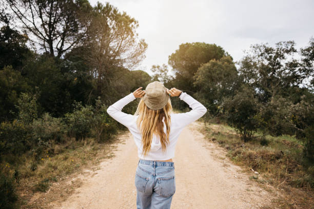 istock Woman wearing a hat walking on a path in a forest 1498516719