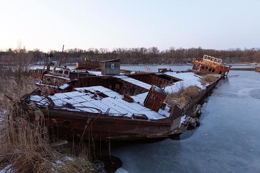 A vintage boat sits atop a frozen lake, blanketed with a layer of snow