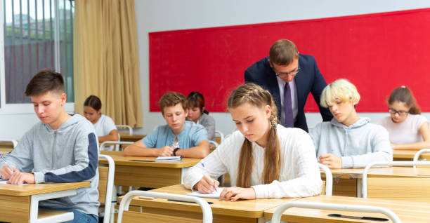 istock Teacher man helping students during lesson in schoolroom 1498519720