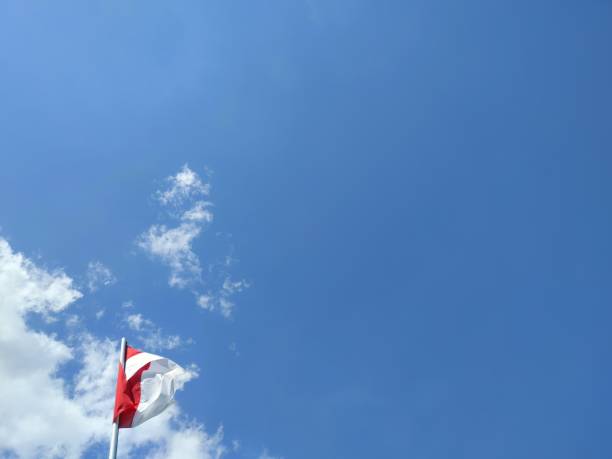 istock Indonesian flag, red and white, with blue sky and white clouds background 1498523052