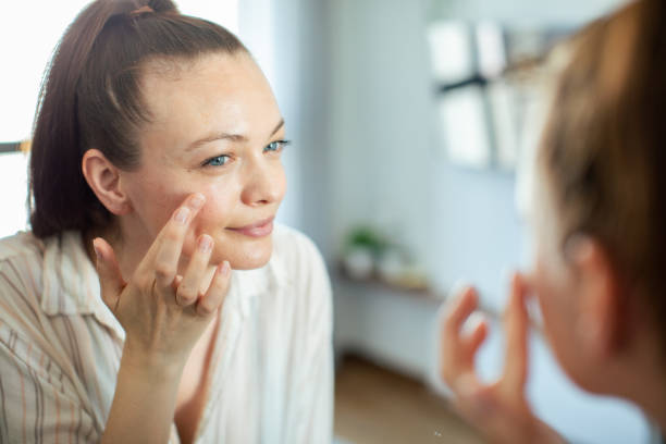 istock Young woman putting on makeup while looking in a mirror at home 1498527652