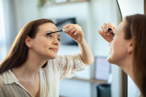 istock Young woman putting on makeup while looking in a mirror at home 1498527813