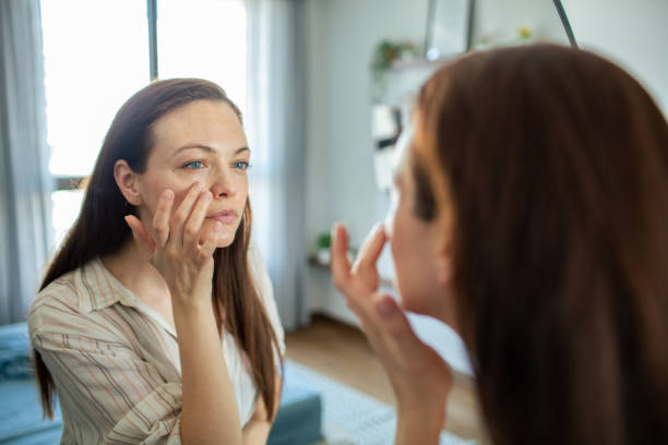 istock Young woman putting on makeup while looking in a mirror at home 1498527890