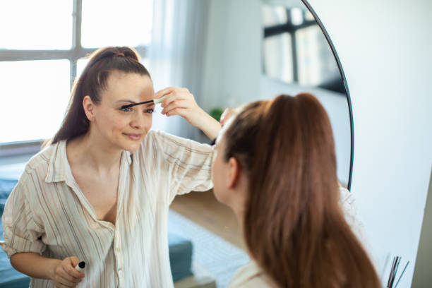 istock Young woman putting on makeup while looking in a mirror at home 1498528007