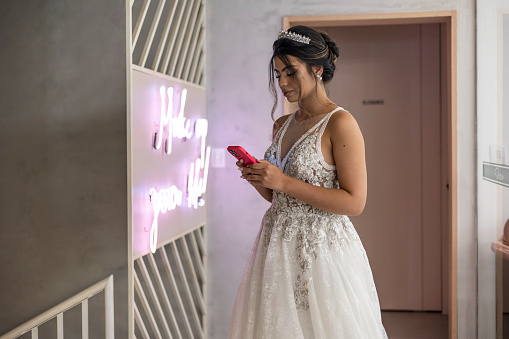 Latin woman dressed as a bride using cell phone