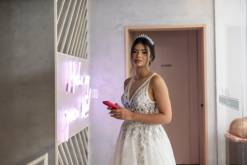 Latin woman dressed as a bride using cell phone